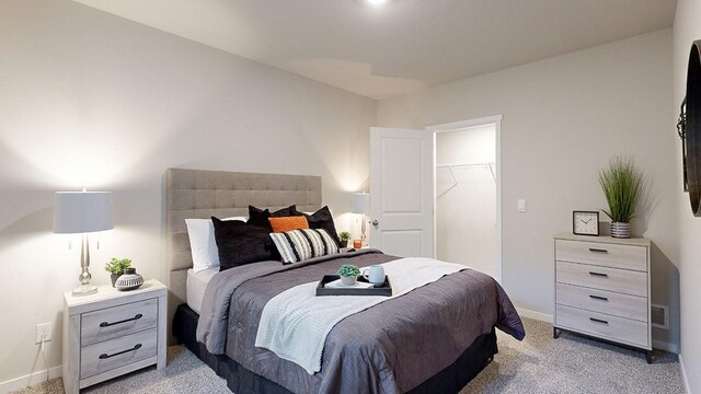 bedroom featuring visible vents, a walk in closet, baseboards, light carpet, and a closet