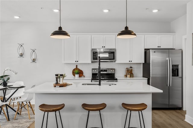 kitchen with white cabinetry, sink, backsplash, a center island with sink, and appliances with stainless steel finishes