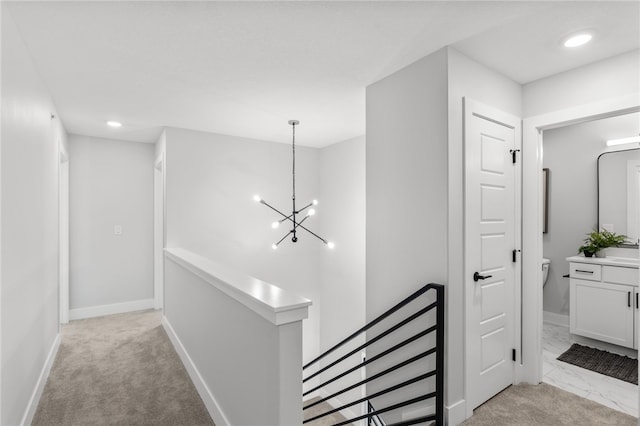 hall featuring light carpet and a notable chandelier