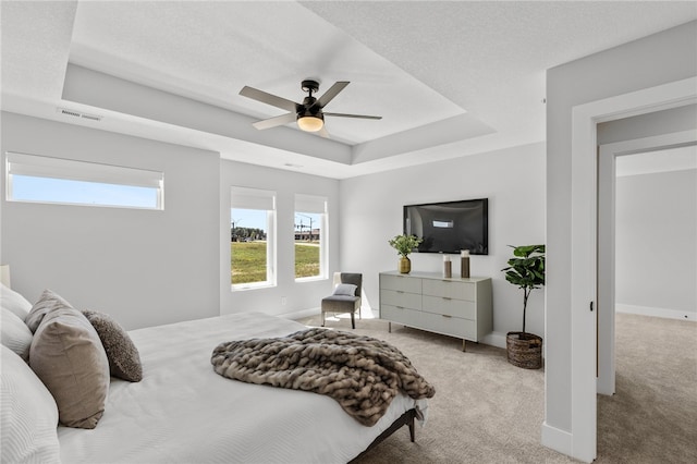 carpeted bedroom featuring a raised ceiling and ceiling fan