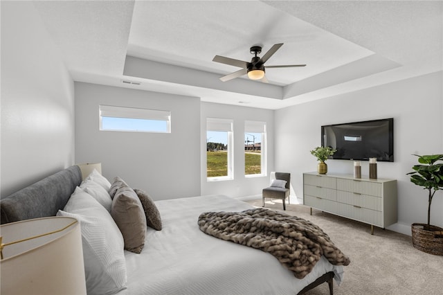 carpeted bedroom featuring a tray ceiling and ceiling fan