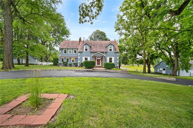 view of front of house featuring a chimney, a front lawn, and stucco siding