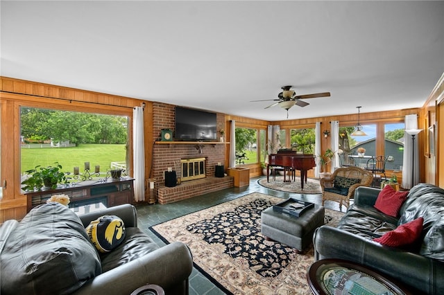 living area featuring a fireplace, plenty of natural light, wooden walls, and ceiling fan