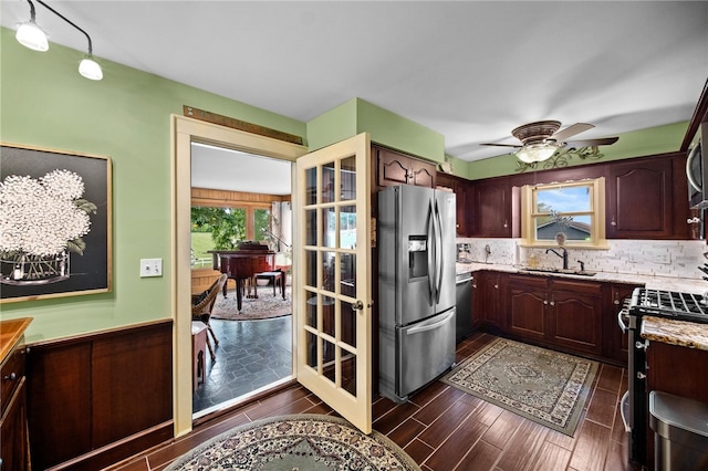 kitchen featuring light stone counters, stainless steel appliances, a sink, wood tiled floor, and tasteful backsplash