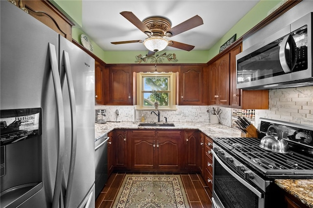 kitchen featuring light stone counters, stainless steel appliances, wood finish floors, a sink, and backsplash