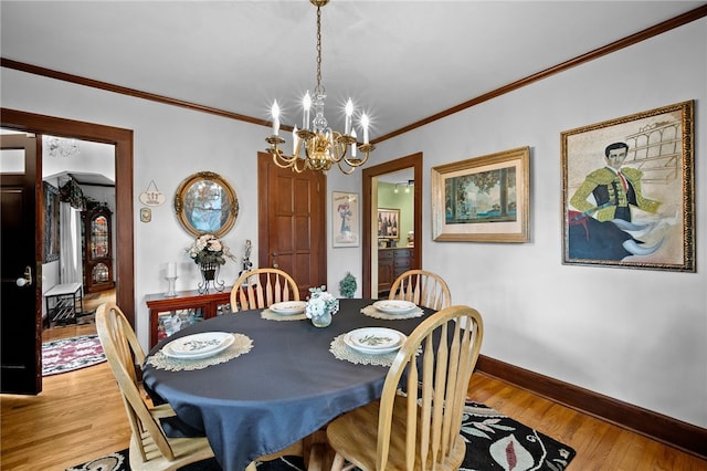 dining area featuring crown molding, light wood finished floors, a notable chandelier, and baseboards