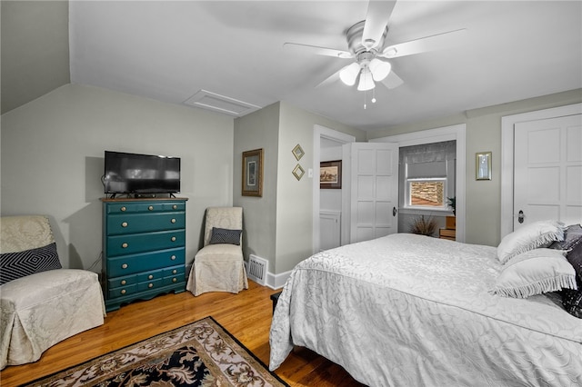 bedroom featuring lofted ceiling, visible vents, attic access, ceiling fan, and wood finished floors