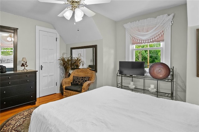 bedroom with a ceiling fan, vaulted ceiling, and wood finished floors