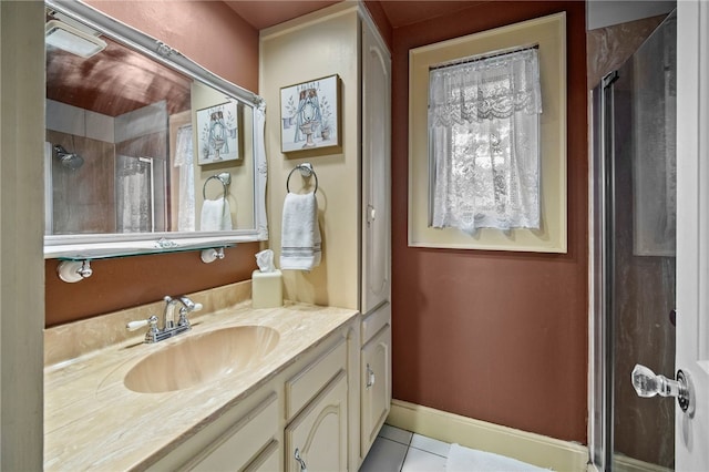 bathroom with a shower with shower door, vanity, baseboards, and tile patterned floors