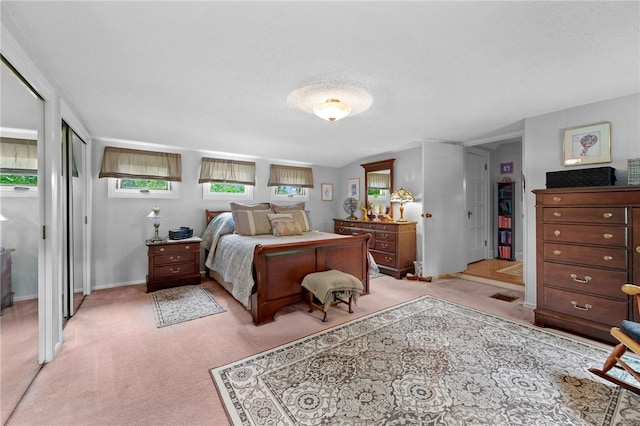 bedroom featuring a textured ceiling, multiple windows, baseboards, and light colored carpet