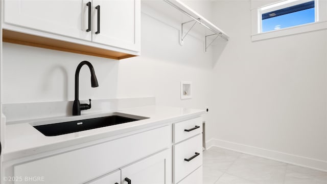 laundry area featuring washer hookup, cabinet space, a sink, and baseboards