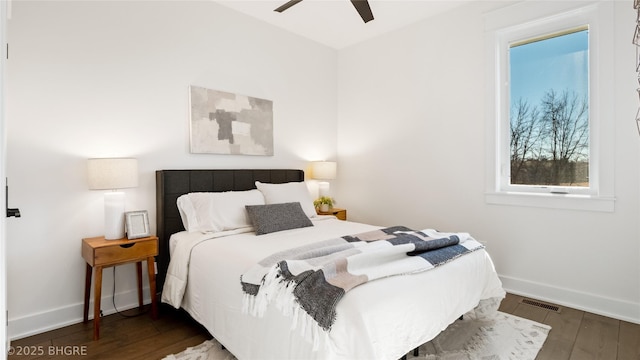 bedroom featuring ceiling fan, visible vents, baseboards, and wood finished floors