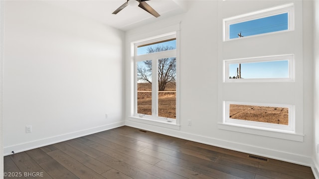 spare room featuring baseboards, visible vents, ceiling fan, and dark wood-type flooring