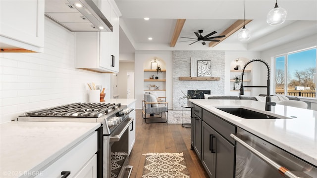 kitchen featuring dark wood finished floors, light countertops, appliances with stainless steel finishes, a sink, and wall chimney range hood