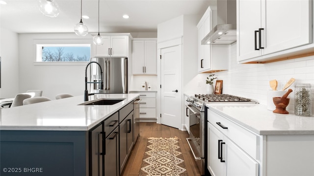 kitchen featuring dark wood-style flooring, decorative light fixtures, stainless steel appliances, wall chimney range hood, and white cabinetry