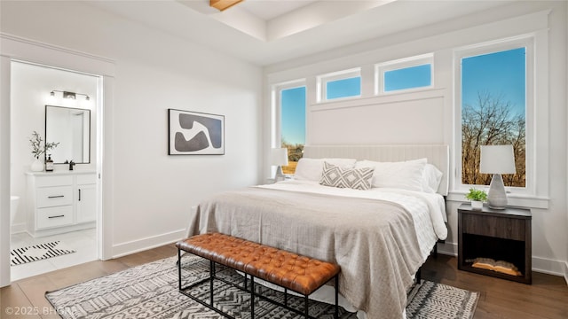 bedroom with a sink, ensuite bath, baseboards, and wood finished floors