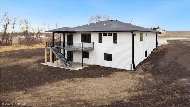 back of property featuring a patio area, stairway, a deck, and roof with shingles