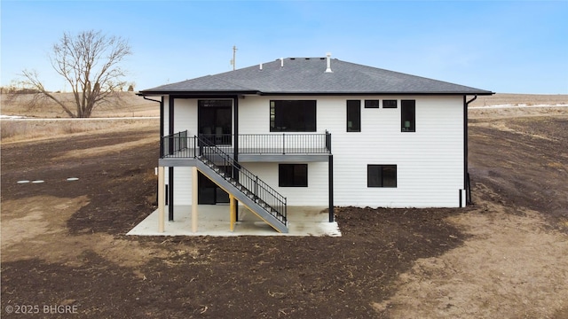 back of house featuring roof with shingles, stairway, and a patio area