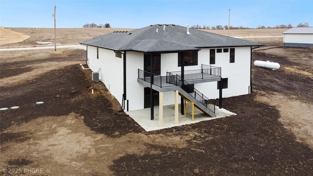 rear view of house with roof with shingles, a patio, stairway, central AC unit, and a deck