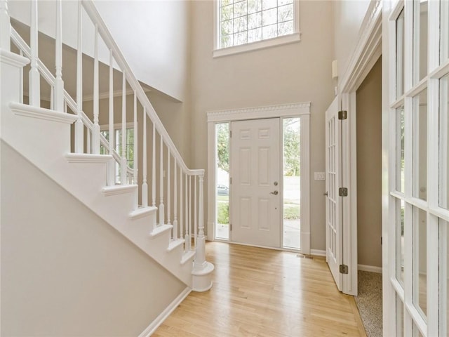 entrance foyer featuring a towering ceiling and light hardwood / wood-style floors