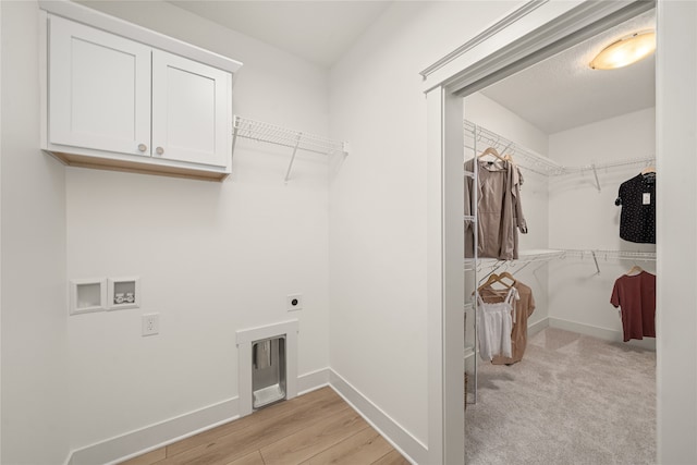 laundry area with electric dryer hookup, cabinets, light wood-type flooring, and washer hookup