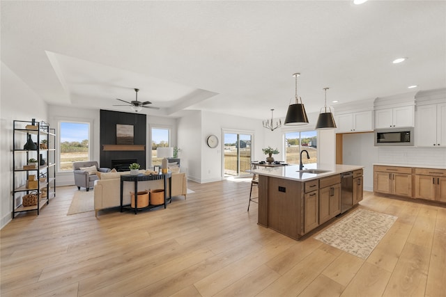 kitchen featuring built in microwave, sink, stainless steel dishwasher, an island with sink, and a fireplace