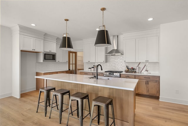 kitchen with pendant lighting, white cabinets, sink, wall chimney exhaust hood, and a large island