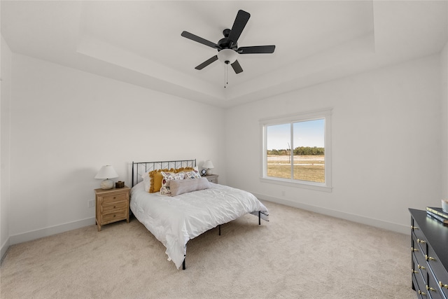 carpeted bedroom featuring a raised ceiling and ceiling fan