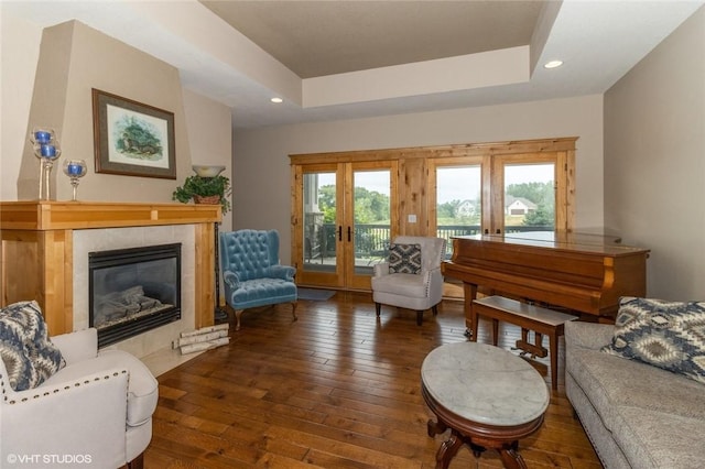 living room with dark hardwood / wood-style flooring, a raised ceiling, a fireplace, and french doors