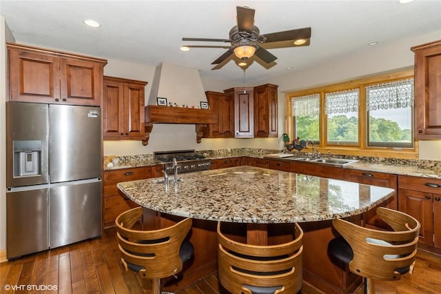 kitchen featuring light stone counters, a kitchen island, stainless steel appliances, and custom range hood