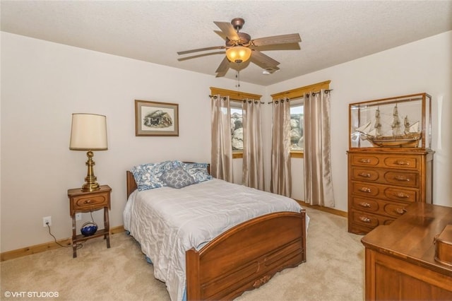 bedroom with a textured ceiling, light colored carpet, and ceiling fan