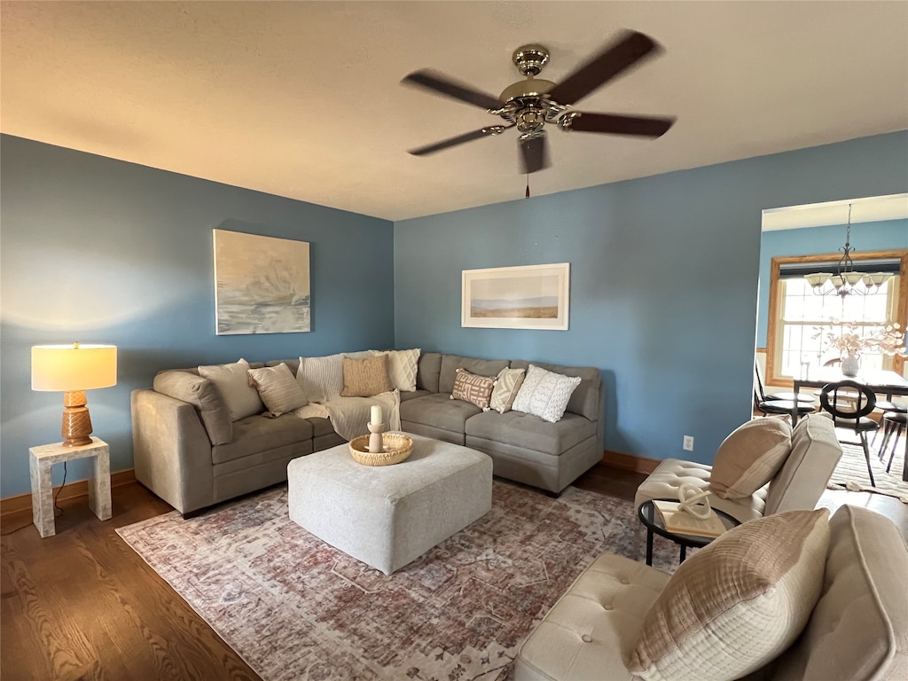 living room with ceiling fan with notable chandelier and dark hardwood / wood-style floors