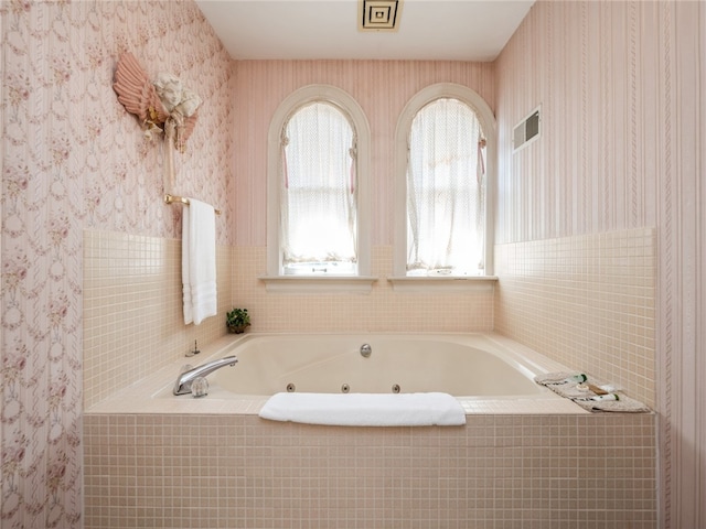 bathroom with a relaxing tiled tub and tile walls