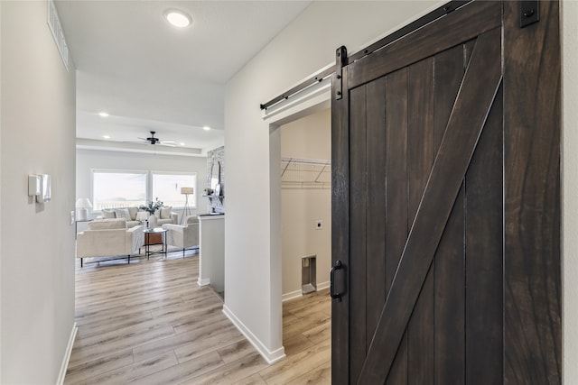 corridor featuring a barn door and light hardwood / wood-style floors