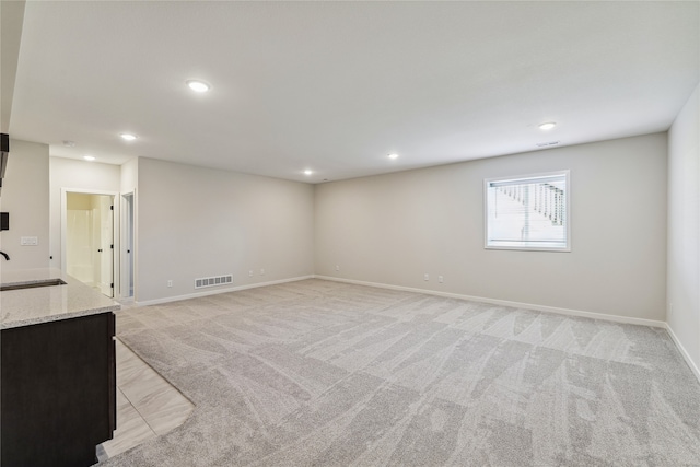 unfurnished living room featuring sink and light carpet