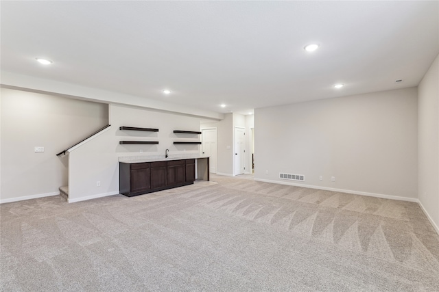 unfurnished living room featuring indoor bar and light carpet