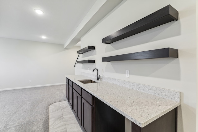 kitchen with sink, light carpet, and light stone counters