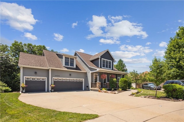 view of front of home with a front yard, covered porch, and a garage