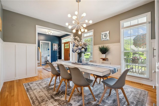 dining space with light wood-type flooring and an inviting chandelier