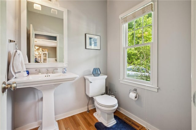 bathroom featuring wood-type flooring, toilet, and a notable chandelier