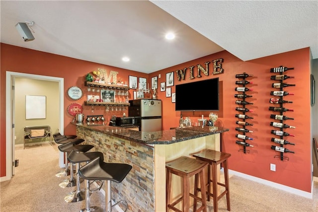 bar with light carpet and stainless steel fridge