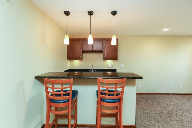 kitchen with carpet floors, a breakfast bar area, kitchen peninsula, and pendant lighting