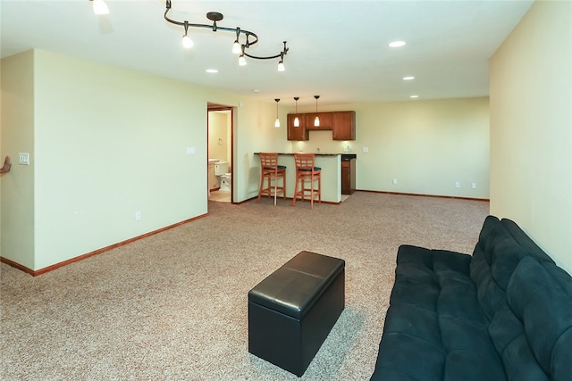 carpeted living room featuring bar area and rail lighting