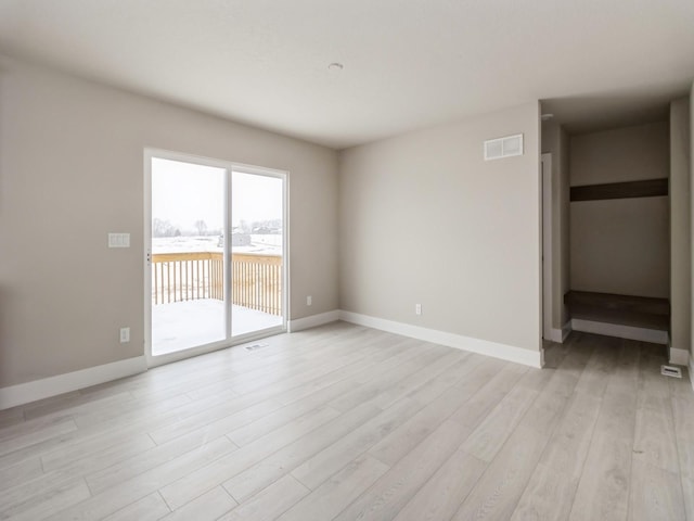 unfurnished room featuring light wood-type flooring, visible vents, and baseboards