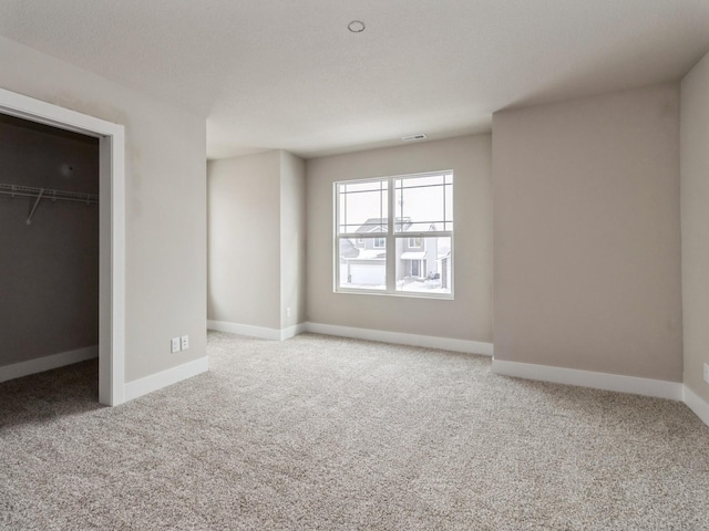 unfurnished bedroom with visible vents, carpet flooring, a walk in closet, and baseboards