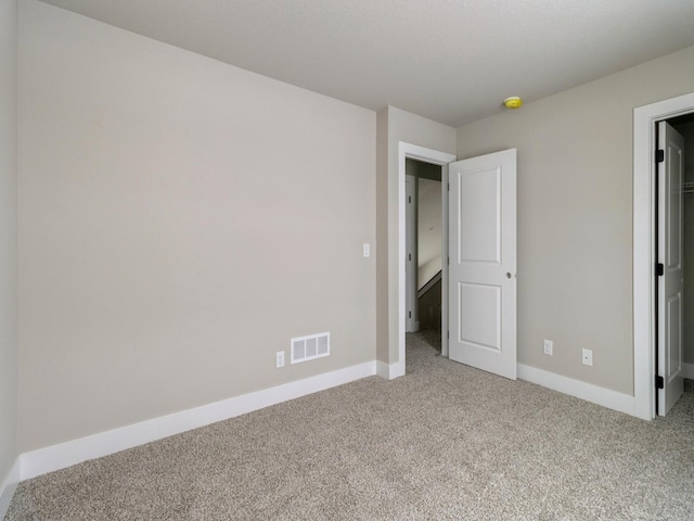 unfurnished bedroom with visible vents, light carpet, baseboards, and a spacious closet