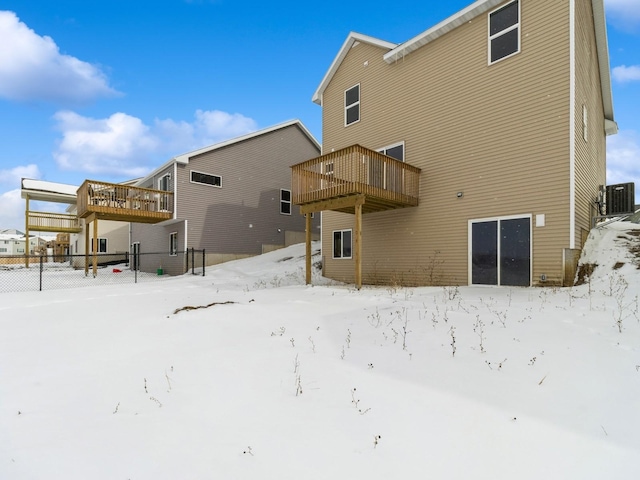 snow covered back of property featuring central air condition unit and a wooden deck