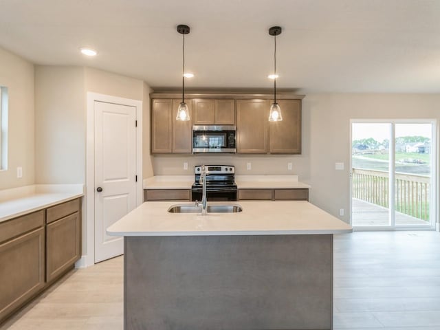 kitchen with light wood-style floors, light countertops, hanging light fixtures, and stainless steel appliances
