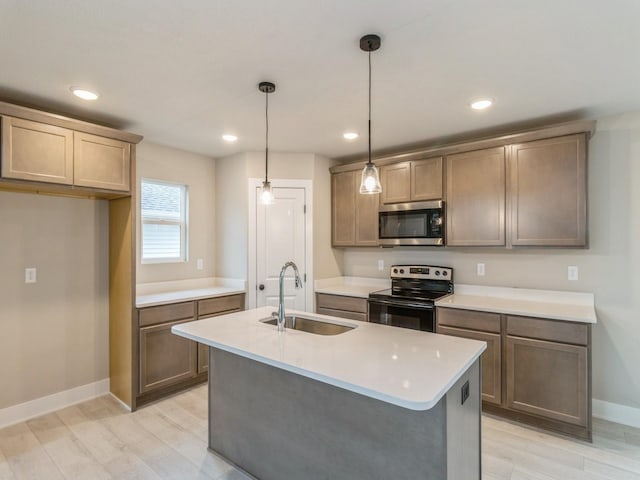 kitchen with appliances with stainless steel finishes, a sink, light countertops, baseboards, and decorative light fixtures