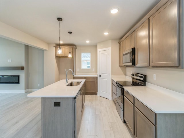 kitchen with an island with sink, light wood-type flooring, recessed lighting, a sink, and stainless steel appliances